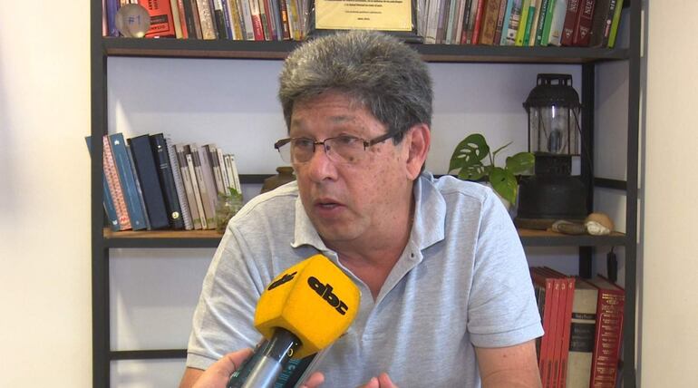 Gustavo Canatta con cabello canoso y gafas, sentado en oficina, gesticulando durante una entrevista con micrófono de ABC Color.