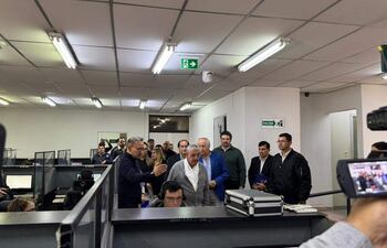 Isaías Fretes en conferencia, rodeado de un grupo de personas, observando atentamente y tomando notas.