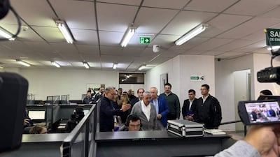 Isaías Fretes en conferencia, rodeado de un grupo de personas, observando atentamente y tomando notas.