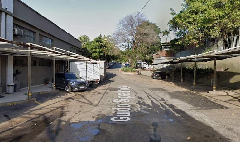 Calle pavimentada en Asunción, con vehículos estacionados y árboles a los costados, creando un ambiente tranquilo y solitario.