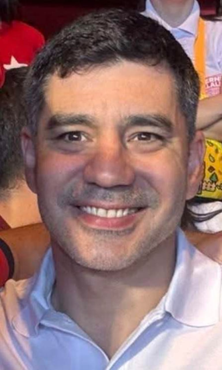 Persona con sonrisa amplia y hoyuelos, mostrando felicidad en un ambiente animado.