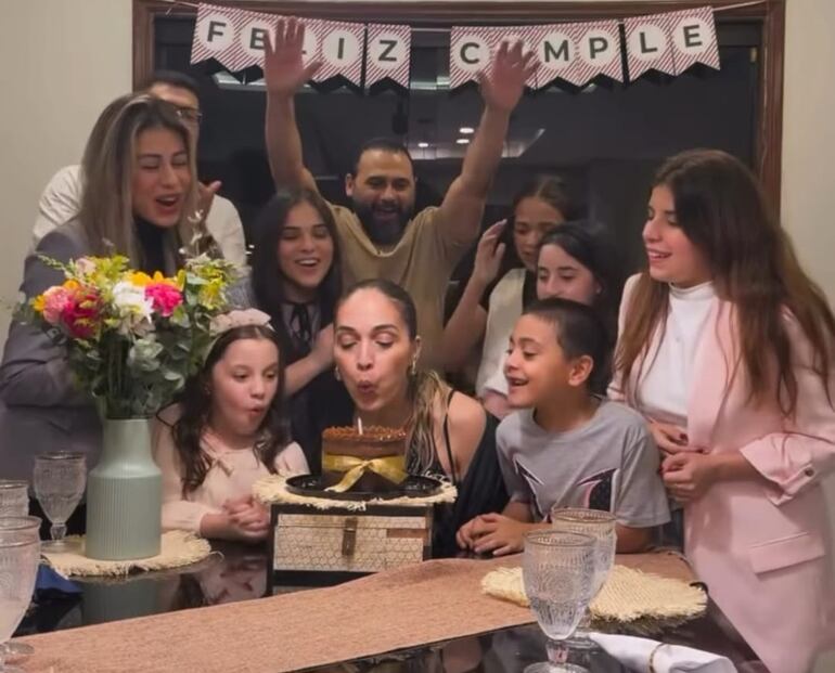 Jazmín Luraghi a punto de apagar la velita de la tradicional torta de cumpleaños, rodeada de su esposo Maxi Biancucchi, sus hijos y amigos. (Captura de la historia de Instagram de Jazmín Luraghi)