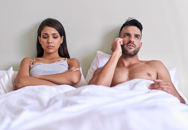 Pareja cansada en la cama, imagen ilustrativa.