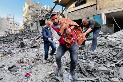 Tres hombres rescatan un cadáver de entre los escombros de un edificio destruido por un bombardeo israelí, el martes en Beit Lahia, en el norte de la Franja de Gaza.