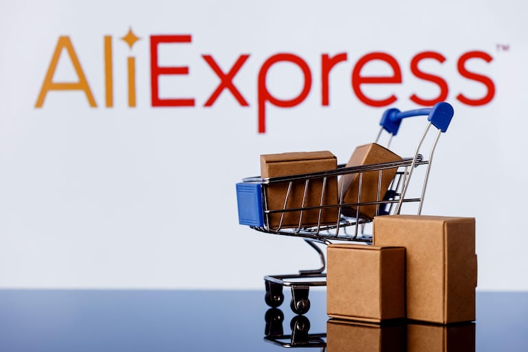 Carrito de compras metálico azul con cajas marrones apiladas, destacado el logo rojo de AliExpress en un fondo blanco.