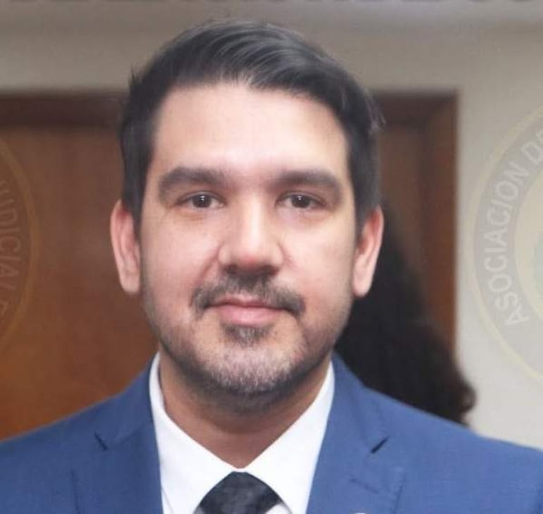 Hombre con traje azul y corbata negra mirando a la cámara en un despacho de la Asociación Judicial.