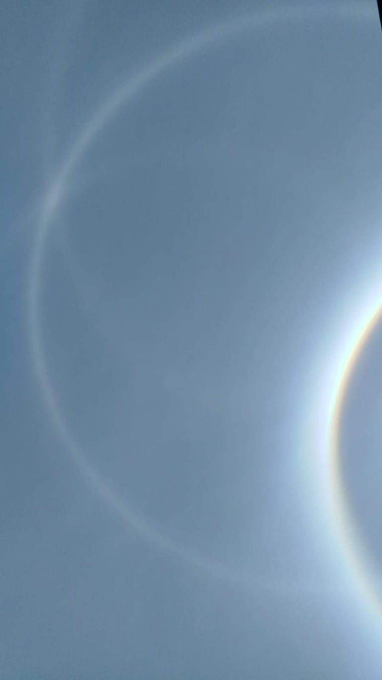 Cielo con halo solar visible, mostrando círculos concéntricos de colores suaves alrededor del sol en un día claro.