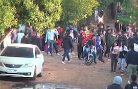 Treinta personas, la mayoría con abrigo, rodean una motocicleta en un ambiente de preocupación tras disturbios.