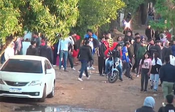 Treinta personas, la mayoría con abrigo, rodean una motocicleta en un ambiente de preocupación tras disturbios.