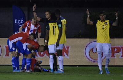 Robert Morales, sentido en el campo, rodeado por los jugadores de la selección paraguaya y ecuatoriana después de sufrir un golpe en la rodilla derecha.
