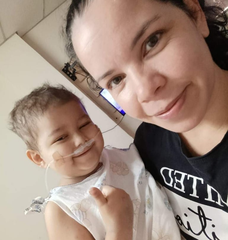 Blanca Guerrero en camiseta oscura junto a su hijo Nico, con pijama claro y sonrisa, en un ambiente hospitalario.