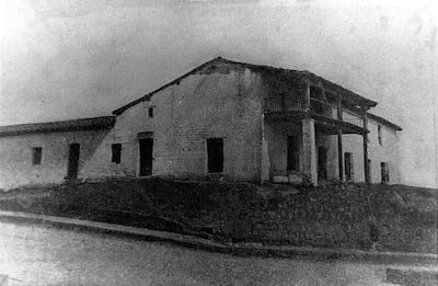 Construcción colonial de ladrillo con ventanales y terraza en un paisaje elevado, sin personas presentes.
