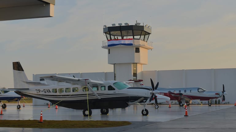 Aeropuerto en San Juan del Paraná con aviones ZP-GVA y otro gris y rojo, torre de control visible con bandera paraguaya.