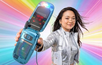 Mujer con chaqueta plateada y teléfono Commodore, sonriente, rodeada de luces coloridas en un escenario vibrante.