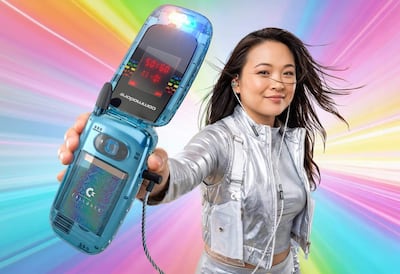 Mujer con chaqueta plateada y teléfono Commodore, sonriente, rodeada de luces coloridas en un escenario vibrante.