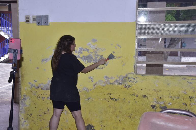 Paredes de la escuela están carcomidas por la humedad. Jóvenes voluntarios retiraron la pintura vieja para volver a pintar las paredes.