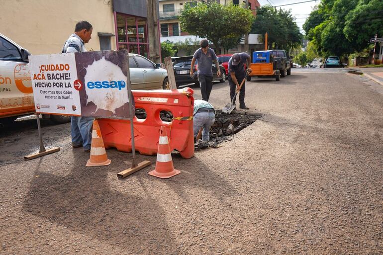 Cinco hombres trabajan en la calle, uno con camiseta clara inspecciona mientras los otros excavan un bache en Encarnación.