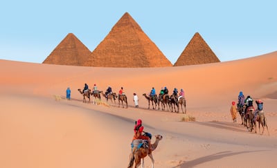 Un grupo de turistas en camello, complejo de la pirámide de Giza, El Cairo, Egipto.