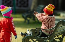 Niños abrigados jugando en una plaza pública.