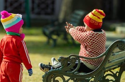Niños abrigados jugando en una plaza pública.