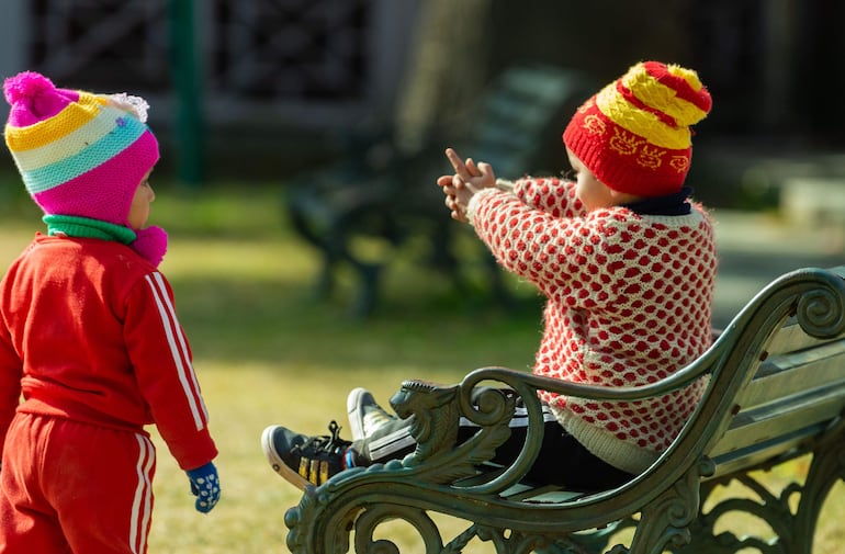 Niños abrigados jugando en una plaza pública.