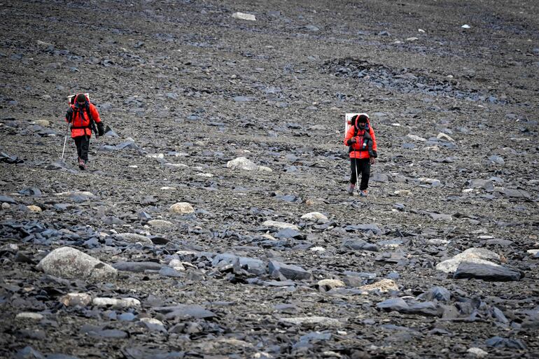 Dos miembros de la expedición 'Pamir-Ice-Memory' descienden del glaciar de Pamir, llevando muestras de núcleos de hielo en una nevera portátil hacia el campamento base en Kon Chukurbashi, Tayikistán Oriental, el 25 de septiembre de 2025.