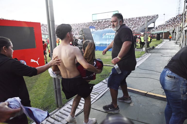 Una mujer hincha de Cerro Porteño retirada tras ser víctima de los efectos de los gases lacrimógenos. 