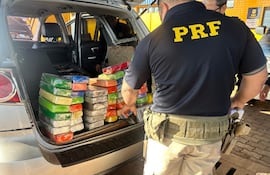 Un agente de la Policía Rodoviaria Federal (PRF) de Brasil con la droga encontrada en la camioneta ocupada por madre e hijo paraguayos, que fue interceptada en la ciudad de Ubiratã.