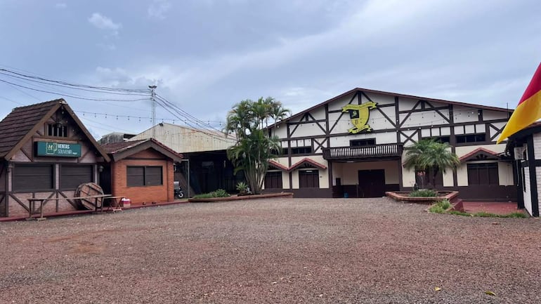 Edificio de estilo arquitectónico con emblema en fachada, rodeado de plantas y sección de ventas de souvenirs.