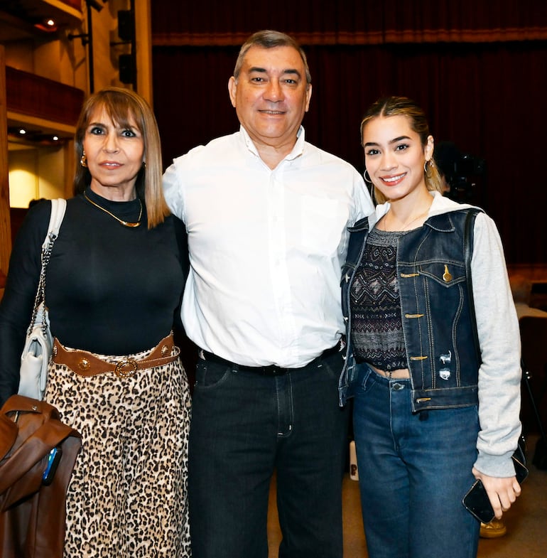 Tres personas sonriendo: mujer con blusa negra y falda de leopardo, hombre maduro en camisa blanca y otra mujer en chaqueta de mezclilla.