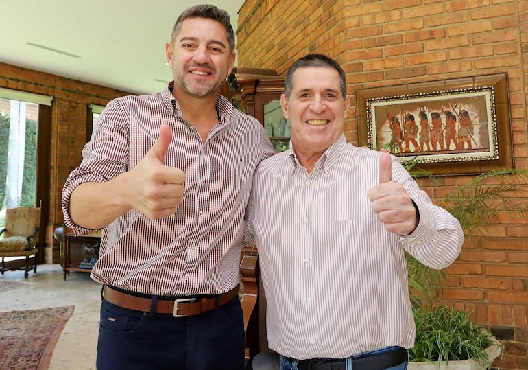 Hercules Pedro Lorenzo Alliana con camisa de cuadros y Horacio Cartes en camisa a rayas levantan el pulgar, sonriendo en un entorno residencial.