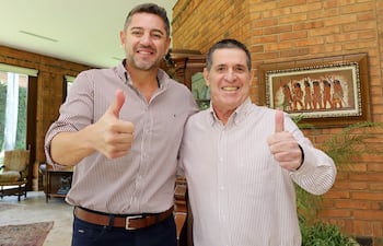 Hercules Pedro Lorenzo Alliana con camisa de cuadros y Horacio Cartes en camisa a rayas levantan el pulgar, sonriendo en un entorno residencial.