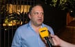 Mario Varela, con camisa celeste, siendo entrevistado con micrófono amarillo en un ambiente oscuro y urbano.