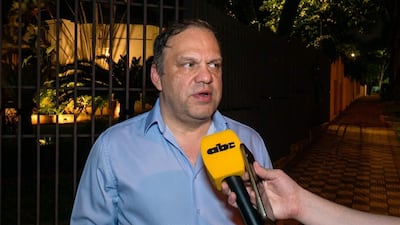 Mario Varela, con camisa celeste, siendo entrevistado con micrófono amarillo en un ambiente oscuro y urbano.