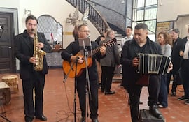 Luis Álvarez y otros músicos con guitarras y acordeones actúan en un ambiente festivo, mostrando expresiones de felicidad y tranquilidad.