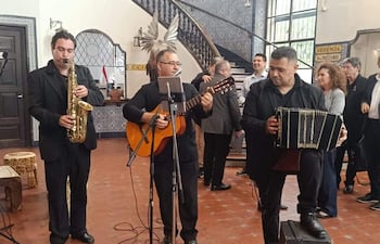 Luis Álvarez y otros músicos con guitarras y acordeones actúan en un ambiente festivo, mostrando expresiones de felicidad y tranquilidad.