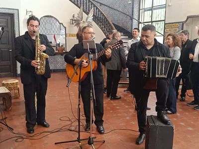 Luis Álvarez y otros músicos con guitarras y acordeones actúan en un ambiente festivo, mostrando expresiones de felicidad y tranquilidad.