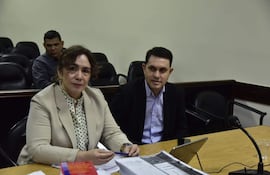 Alba Zaracho con blusa de puntos verdes y chaqueta beige, conversando con Hernán Rivas, mientras un hombre observa en segundo plano.