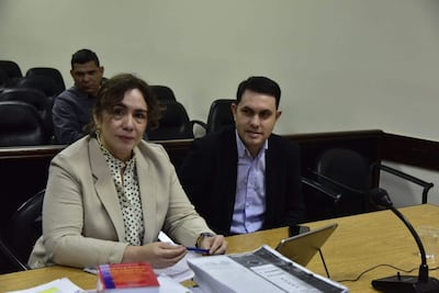 Alba Zaracho con blusa de puntos verdes y chaqueta beige, conversando con Hernán Rivas, mientras un hombre observa en segundo plano.
