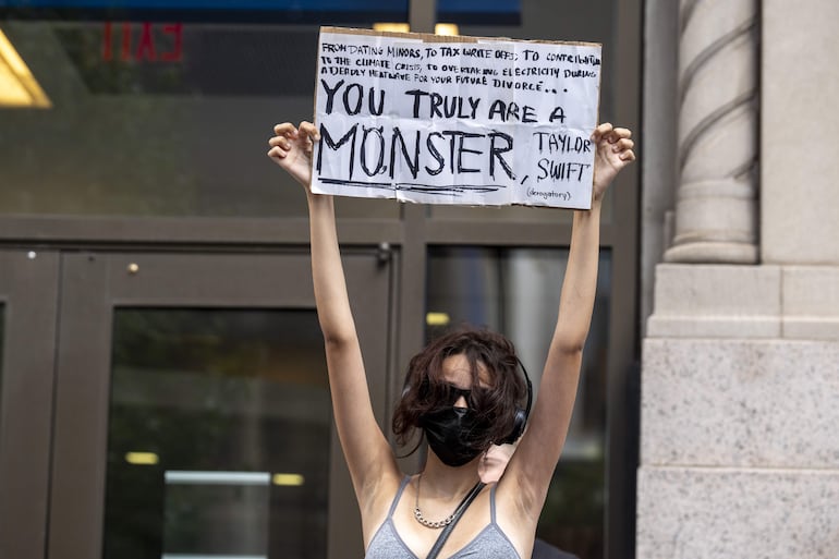 Una mujer sostiene un cartel de protesta durante la boda de la cantante Taylor Swift con el jugador de fútbol americano Travis Kelce este viernes, en los alrededores del Madison Square Garden en Nueva York (Estados Unidos). EFE