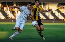 El lateral de Libertad, Iván Ramírez intenta proteger el esférico ante la presión del atacante aurinegro, Derlis Rodríguez.