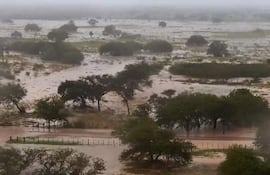 Paisaje inundado con agua cubriendo caminos y vegetación en un ambiente nuboso y lluvioso.