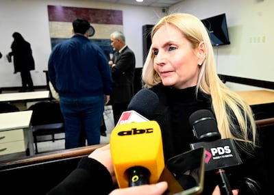 Ana Girala con blusa negra rodeada de micrófonos, mientras tres personas escuchan en el fondo.