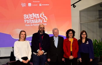 Seis músicos en el escenario, vestidos de negro, tocan violines y cello, mientras el público observa con teléfonos móviles.
