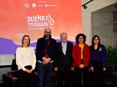 Seis músicos en el escenario, vestidos de negro, tocan violines y cello, mientras el público observa con teléfonos móviles.