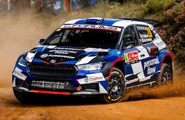 Coche Škoda número 28 compitiendo en rally, mientras espectadores animan desde la ladera en un entorno natural.