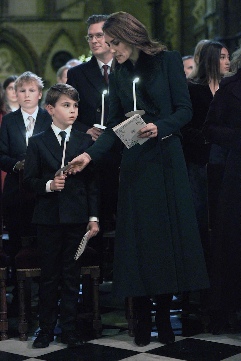 El principito Louis, el más pequeñito de la familia de Kate y William, encendiendo la vela navideña junto a su madre. (Aaron Chown / POOL / AFP)