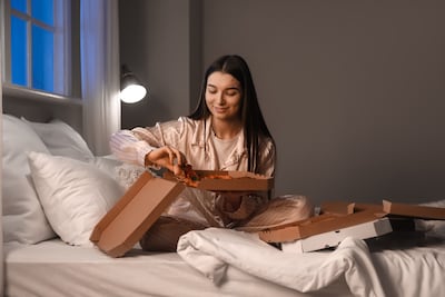 Mujer come pizza en la cama.