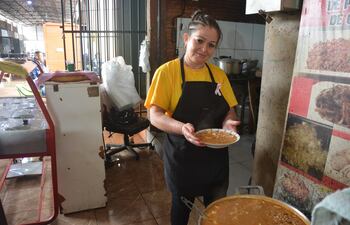 Una mujer muestra el plato del tradicional jopará en su puesto del Mercadito.