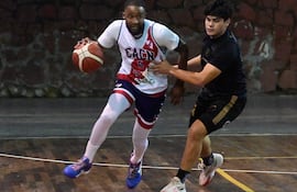 Jugadores de baloncesto en acción: uno en camiseta blanca y el otro en oscuro, ambos concentrados en el juego en un gimnasio.